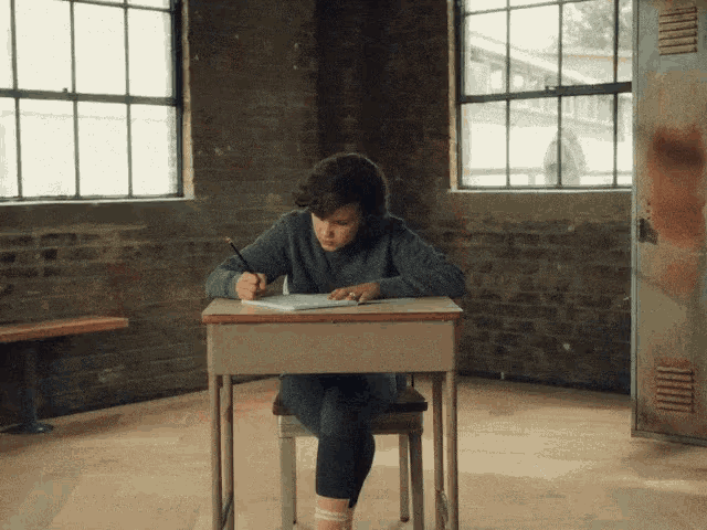 a person is sitting at a desk writing in a notebook