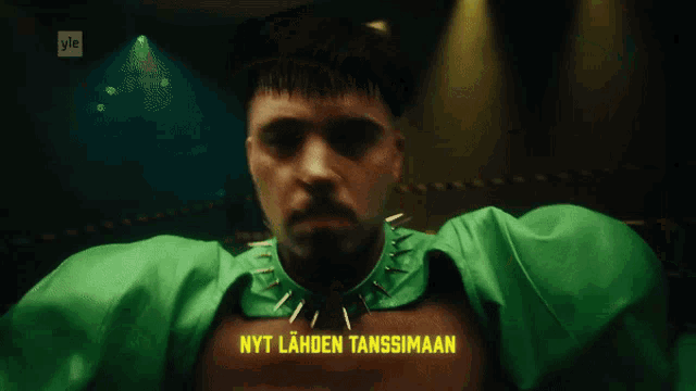 a man in a green cape with nyt laden tanssimaan written on the chest