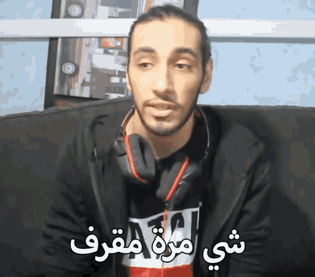 a man wearing headphones is sitting on a couch with arabic writing on the bottom