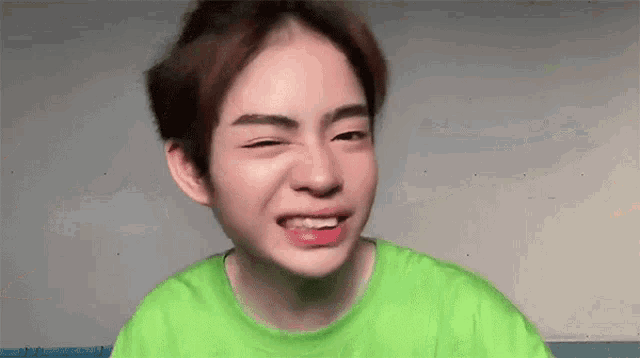 a young boy in a green shirt is making a funny face .
