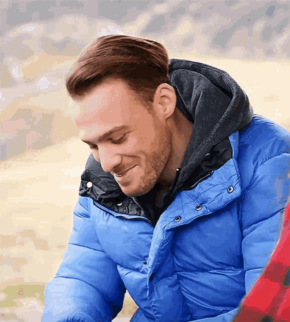 a man in a blue jacket with a hood smiles