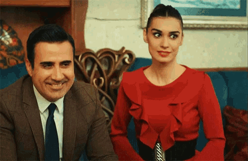 a man in a suit and tie and a woman in a red dress are sitting next to each other