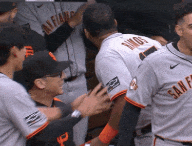a man in a san francisco giants jersey is being hugged