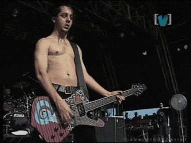 a shirtless man playing a guitar in front of a drum set with the word tama on it