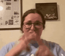 a woman wearing glasses and a blue shirt is making a face .