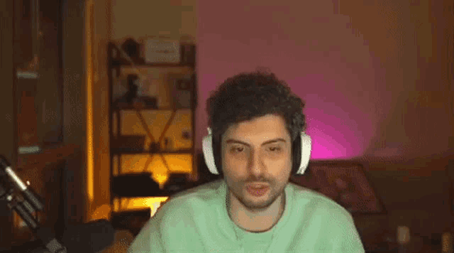a man wearing headphones and a green sweater is smiling