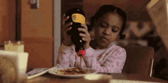 a little girl is pouring liquid from a bottle