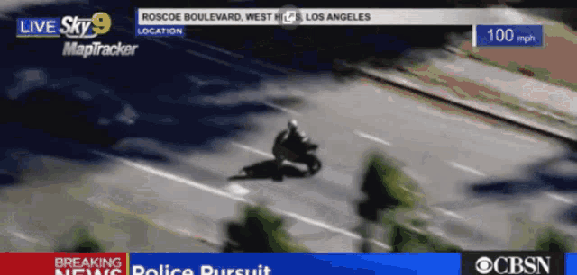 an aerial view of a person riding a motorcycle down a street