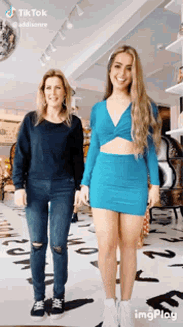 a woman in a blue dress is standing next to a woman in a black shirt in a store .