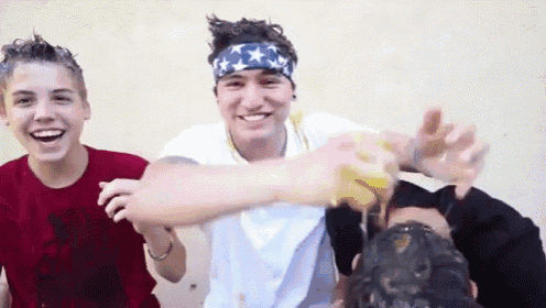 a man wearing an american flag headband is pouring liquid on another man 's head