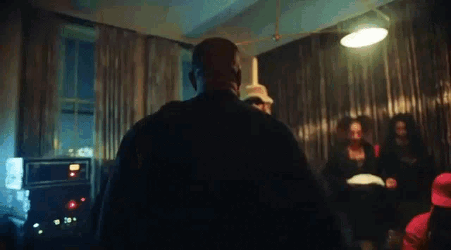 a man in a black jacket is standing in a dark room with a group of people .