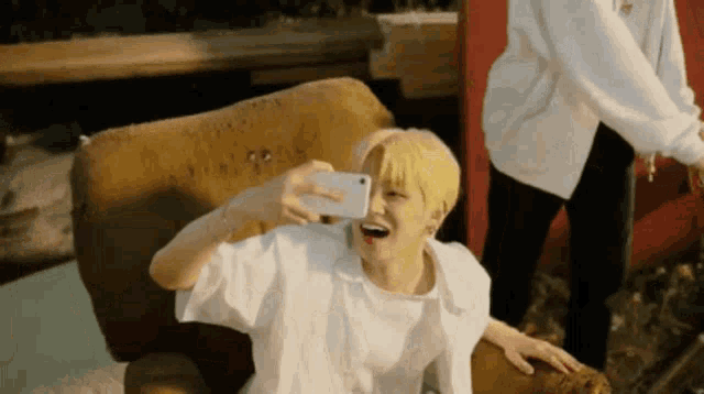 a person with yellow hair is taking a selfie with their phone