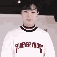 a young man wearing a white sweater that says forever young