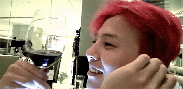 a person with red hair holds a glass of wine