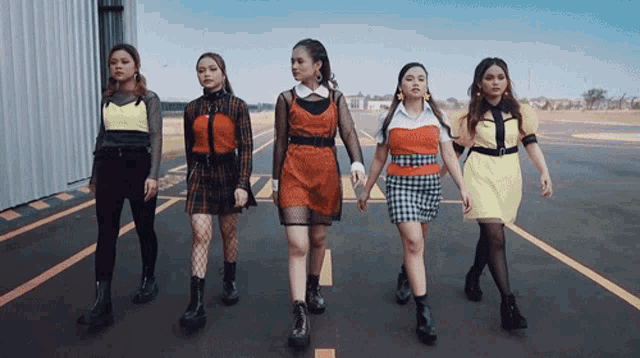 a group of young women are walking down a street holding hands