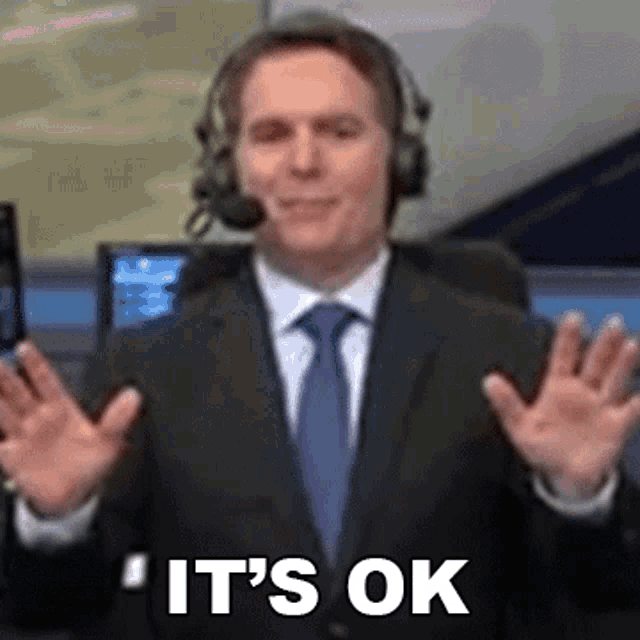 a man in a suit and tie is wearing headphones and saying it 's ok