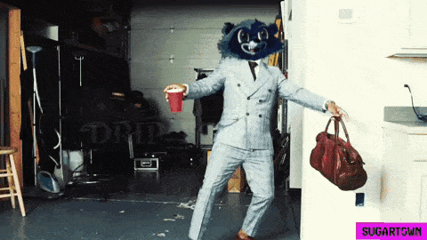 a man in a suit with a raccoon head holding a red cup and a bag