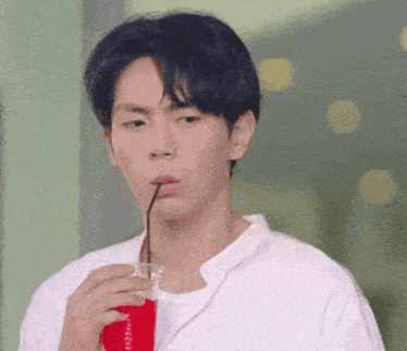 a young man drinking a red drink through a straw