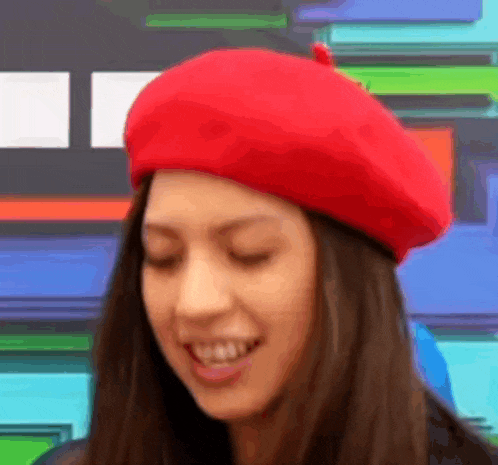 a woman wearing a red beret is smiling and looking at the camera .