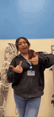 a woman wearing a lanyard that says ns is making a funny face