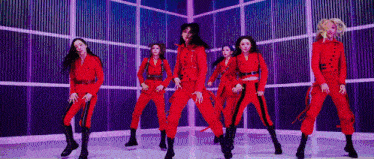 a group of women in red jumpsuits are dancing in a room .