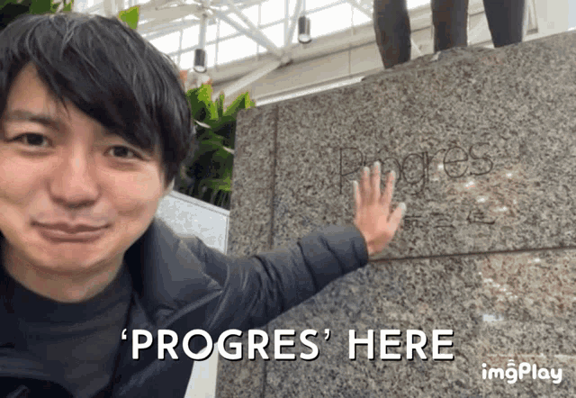 a man 's hand rests on a granite wall with the words progres here written on it