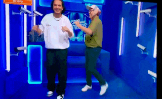 two men are dancing in front of a sign that says " be very careful "