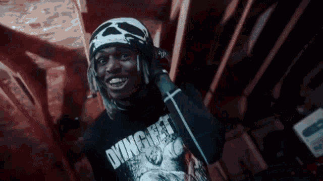 a young man wearing a skull beanie and a t-shirt is holding a microphone .
