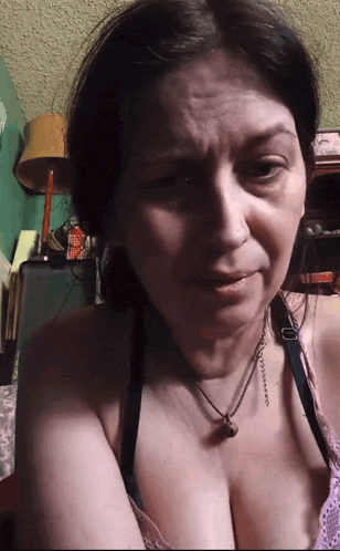 a woman is wearing a bra and a necklace with a bell pendant