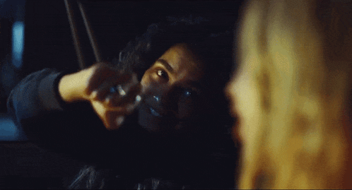 a woman is smoking a cigarette in a dark room while another woman looks on .