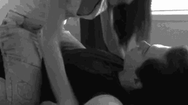 a black and white photo of a woman kissing a man .
