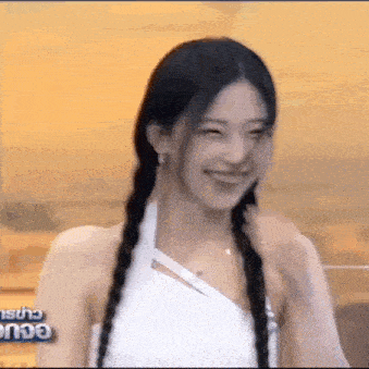 a woman with braids is smiling and laughing while wearing a white dress .