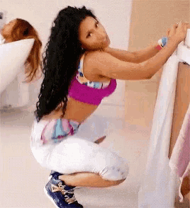 a woman in a purple top and white pants squatting down