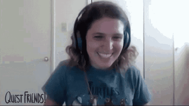 a woman wearing headphones is smiling and wearing a blue shirt .