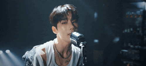 a young man is singing into a microphone in a dark room .