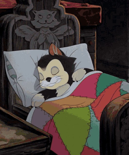 a cartoon cat is sleeping in a bed with a colorful quilt