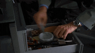 a man in a suit sits at a desk with a clock that says 10:08 on it