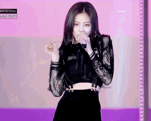 a woman is singing into a microphone while wearing a black top