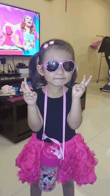 a little girl wearing sunglasses and a pink skirt