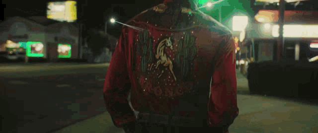 a man in a red jacket with a horse and cactus on the back