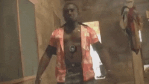 a man is standing in a hallway holding a gun and pointing it at the camera .