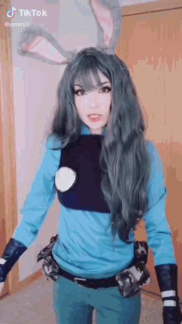 a woman in a costume with bunny ears is standing in front of a wooden door .