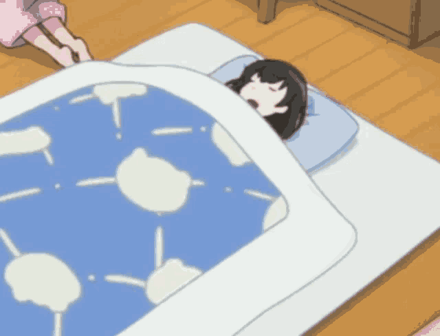 a girl is sleeping on a bed with a blue blanket with white clouds on it