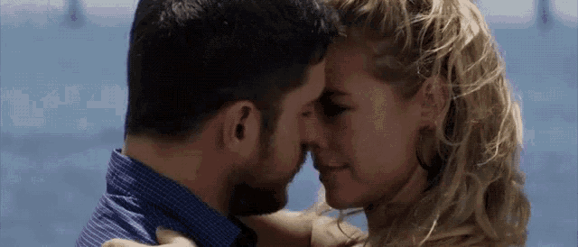 a man and a woman are kissing each other in front of the ocean .