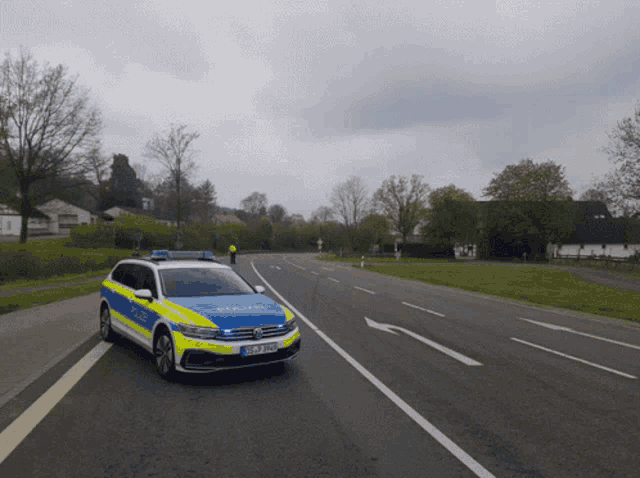 a blue and yellow police car is driving down a street