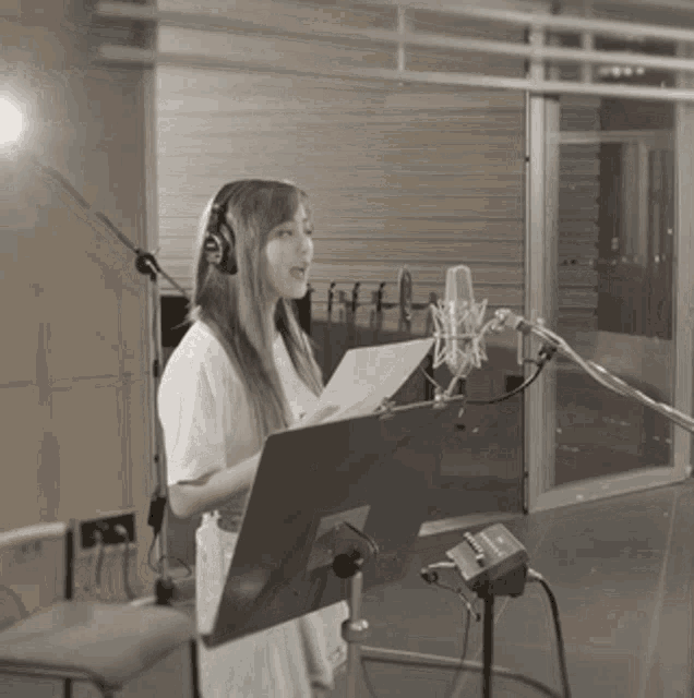 a woman wearing headphones is singing into a microphone in a recording studio