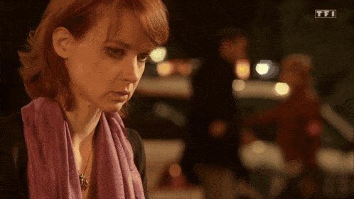 a woman wearing a purple scarf and a necklace with tfi on the bottom