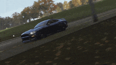 a blue car with a red stripe on the front is driving down a road