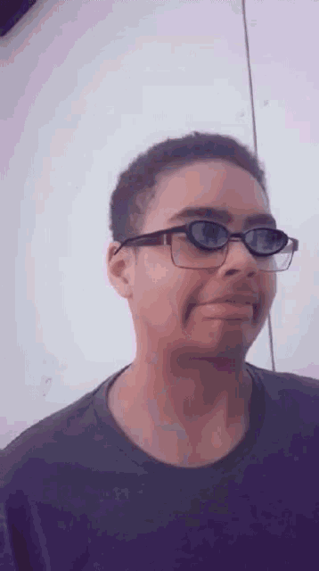 a young man wearing glasses and a purple shirt making a funny face