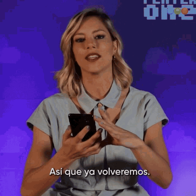 a woman holding a cell phone says " así que ya volveremos " in spanish